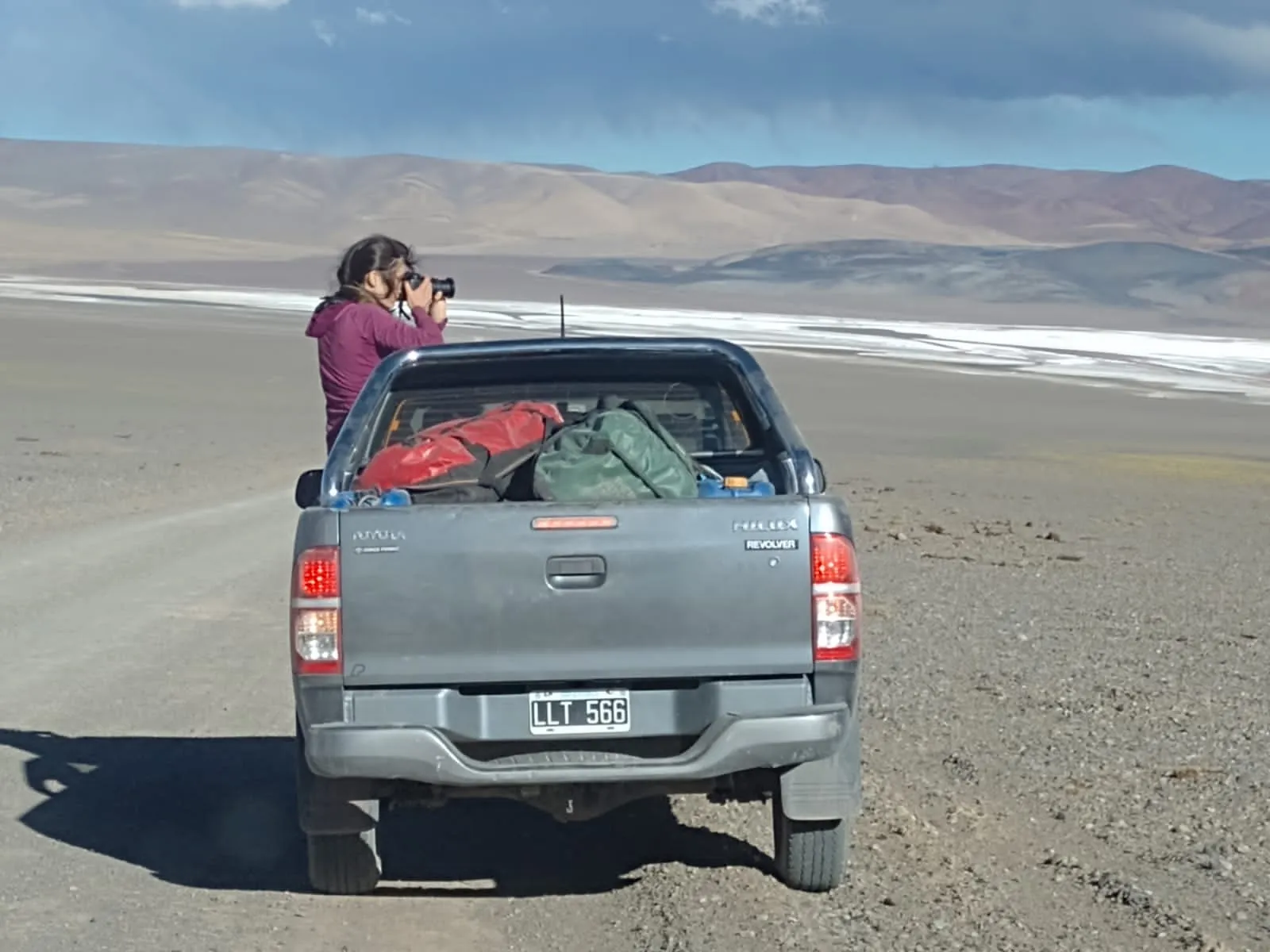 Camioneta de expedición y viajera fotografiando el paisaje de alta montaña