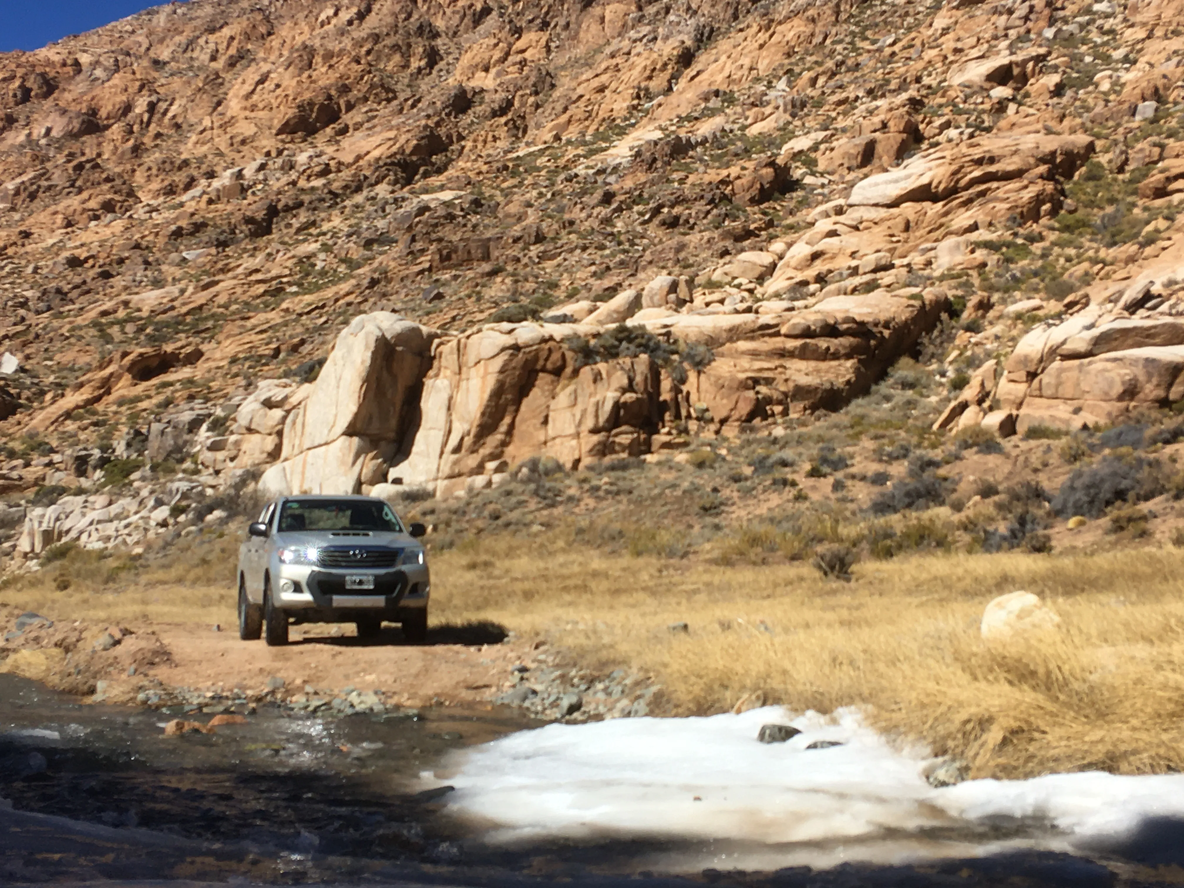Vehículo de montaña cruzando un arroyo entre formaciones rocosas